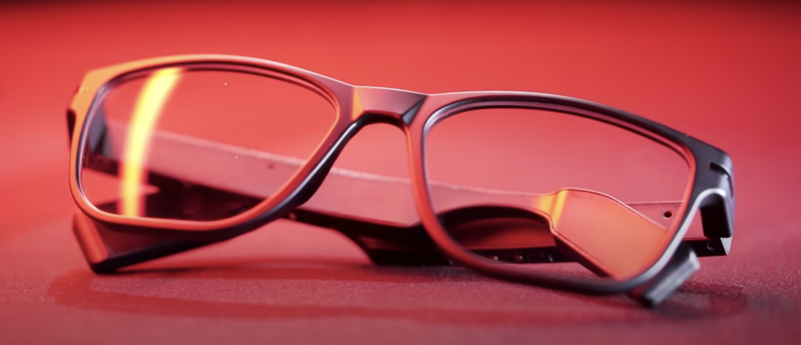 Titan EYEx smart glasses folded on a red surface, temple electronics visible