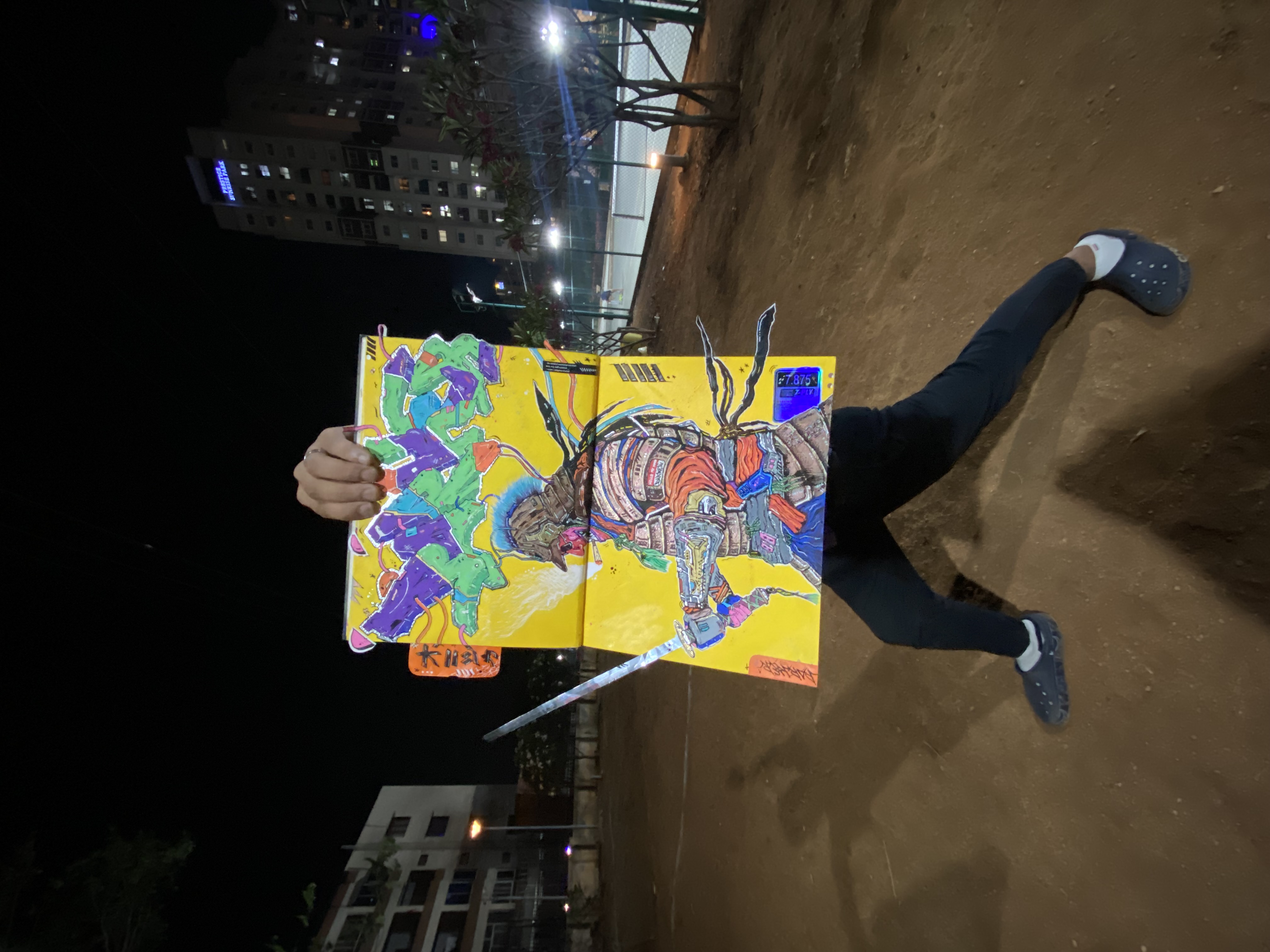 Aayush holding up a colourful painting outdoors